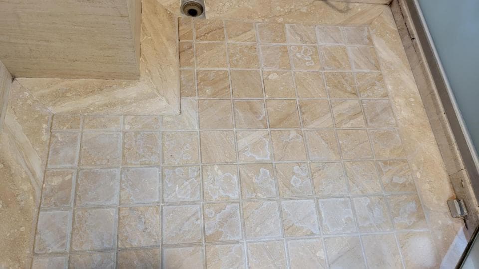 這張照片是一個浴室地板,地板上鋪滿了白色和米色的瓷磚,看起來乾淨整潔。