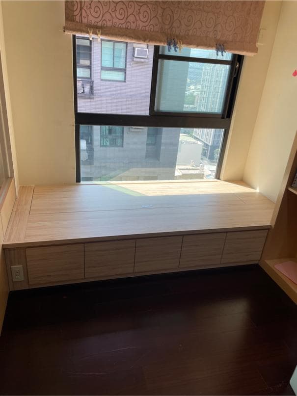 1) 這是一張室內照片,照片中展示了一個木質窗台,窗台上有三抽屜,窗台下方的地板是深色的木質地板,窗台上方的窗戶是落地窗,窗戶上有一個粉色窗簾