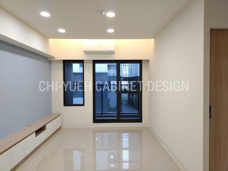 1) 照片顯示一個現代簡約的客廳,地板採用米白色磁磚,牆面為白色,天花板安裝有嵌入式燈,客廳的左側有一面牆是藍色的,右邊是牆面,客廳中間有一台白色電視櫃,電視櫃的下方是抽屜,客廳的右邊有一個木門,客廳的正前方是落地窗,落地窗的左側是一扇窗戶,窗外是建築物