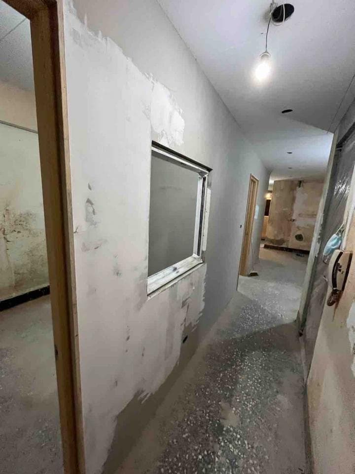 1) 照片顯示一個正在翻新的走廊,走廊牆壁上有一個窗戶