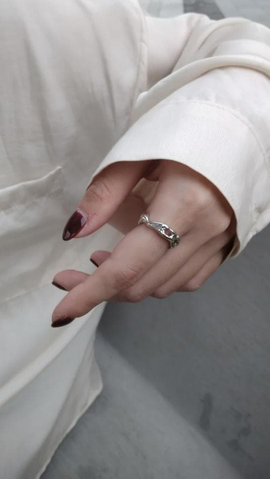 1) 照片中有一隻戴著銀色戒指的手,手指甲塗著深紅色的指甲油,背景是白色的襯衫