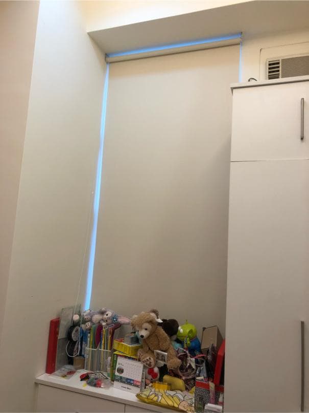 1) 照片顯示一個房間的角落,牆壁上有百葉窗,下方放著一些玩具和書籍