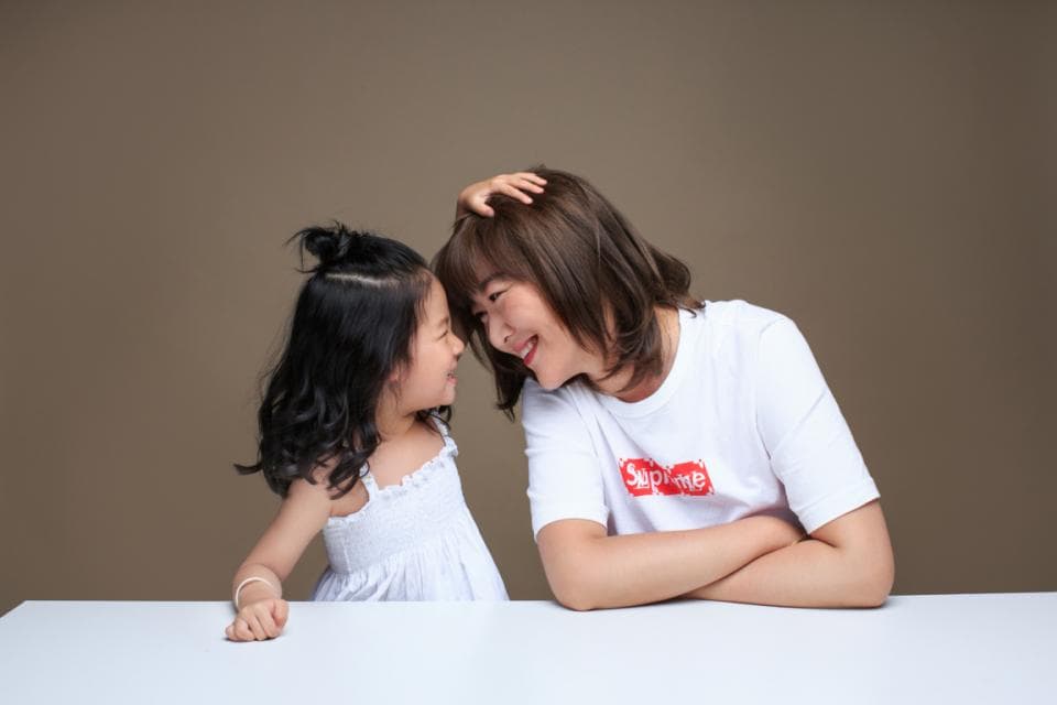 這張照片是一對母女,她們在親密地依偎在一起。母親正用手輕輕地撫摸著女兒的頭,她們的臉上都洋溢著幸福的笑容。