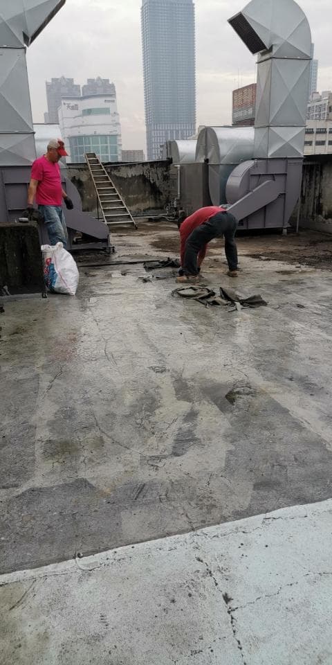 1) 照片顯示一個混凝土屋頂,兩個男人正在修理一個大型通風機