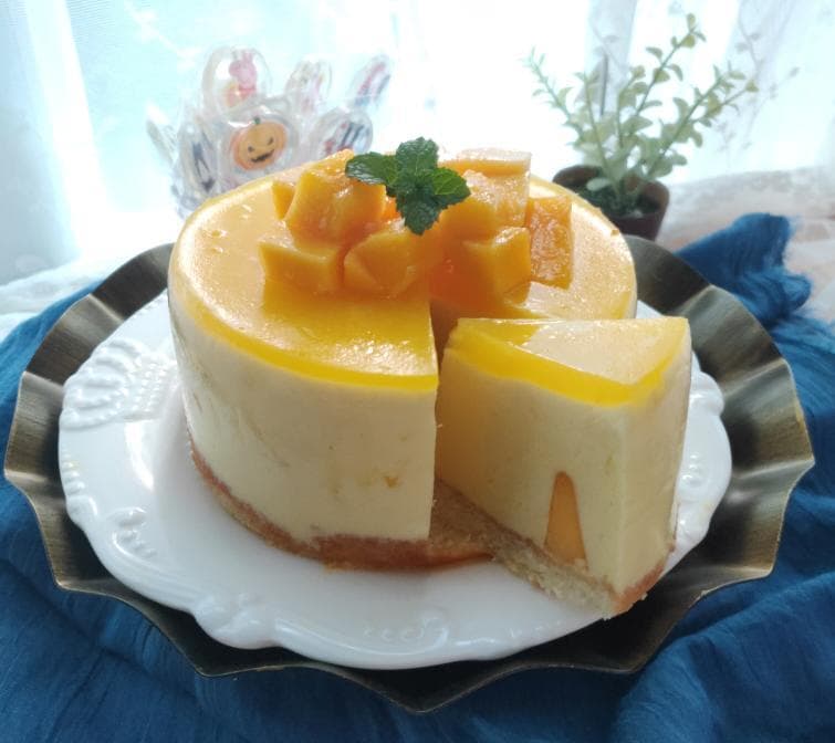 這張照片是一塊芒果慕斯蛋糕,上面放著新鮮的芒果切片,看起來非常美味。