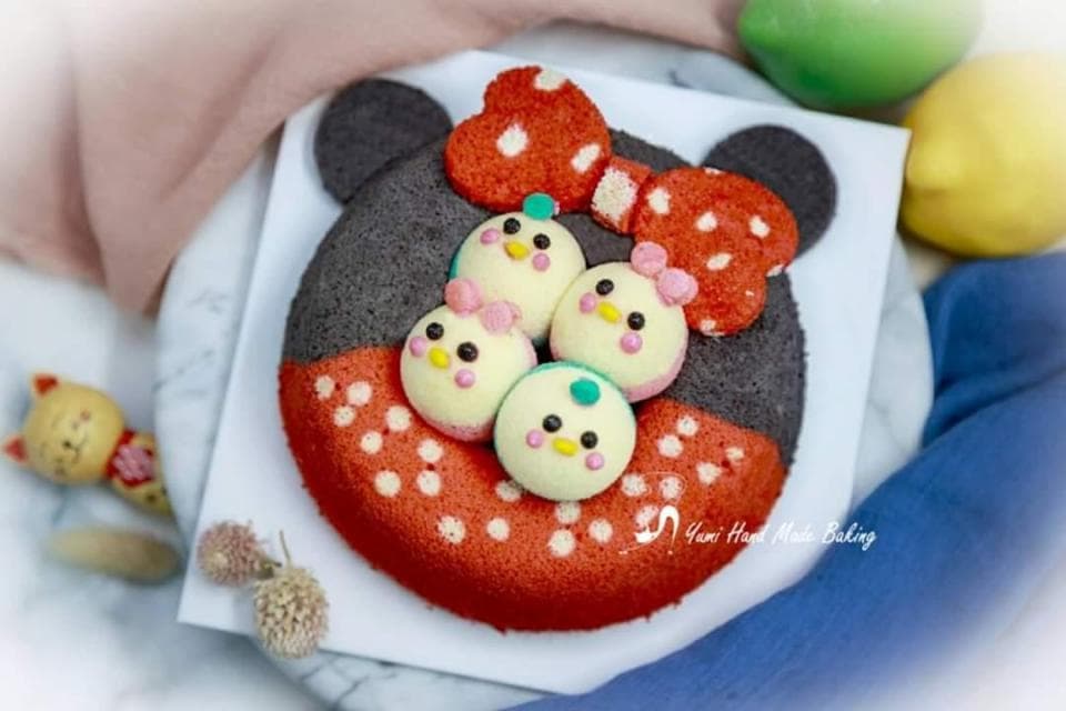 這張照片是一個米奇造型的蛋糕,上面裝飾著四個可愛的小雞造型蛋糕。蛋糕的顏色鮮豔,看起來很美味。