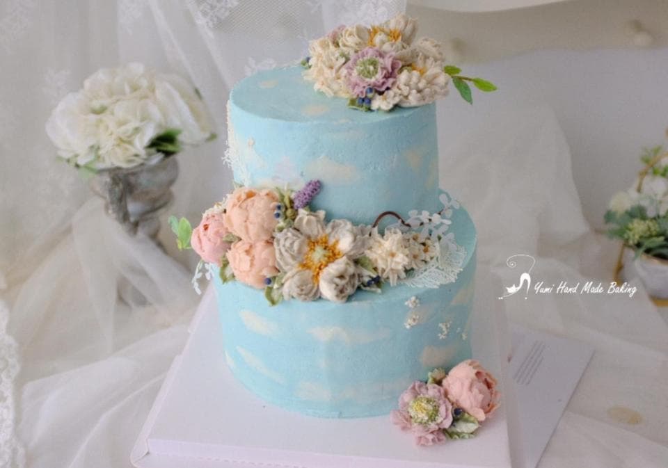 這張照片是一塊兩層的蛋糕,上面裝飾著精緻的糖霜花朵,花朵色彩鮮豔,層層疊疊,令人賞心悅目。