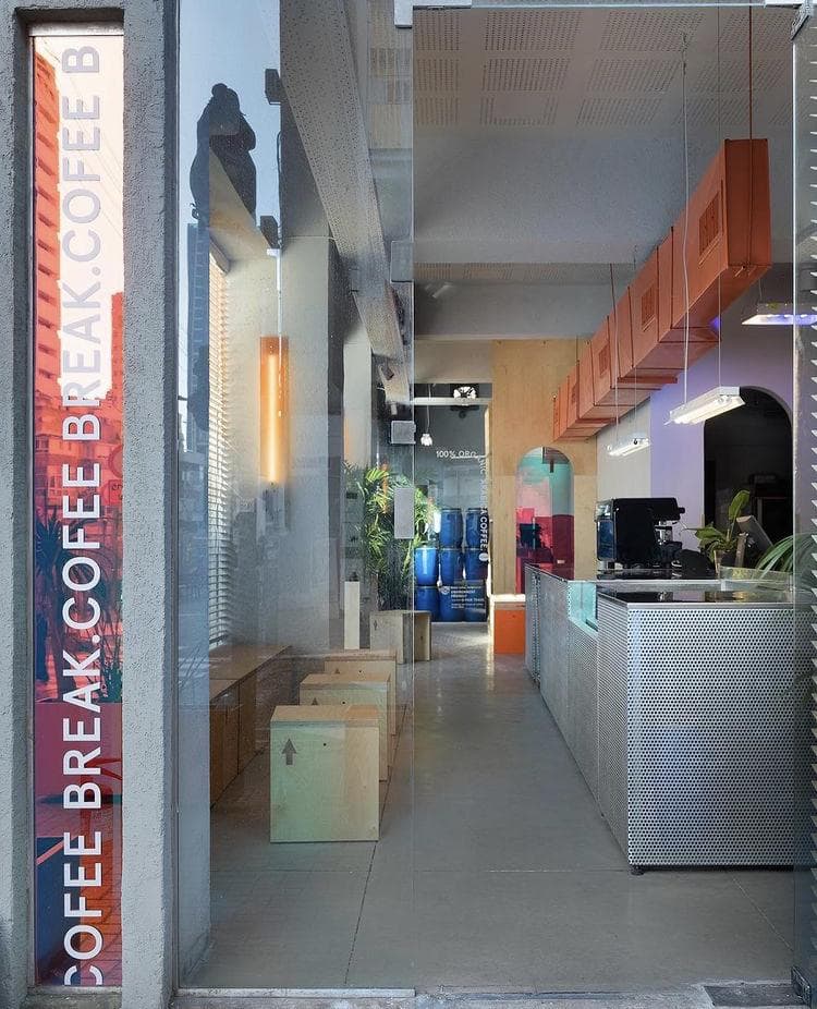 這張「咖啡店」的照片是一個現代化的咖啡店,店裡有木製的桌子和椅子,以及金屬的吧檯。