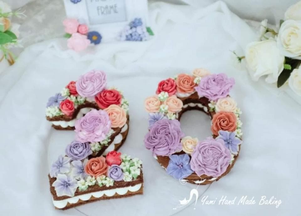 這張照片是兩個用鮮奶油做成的蛋糕,形狀是數字「20」,上面裝飾著各種鮮豔的花朵,非常漂亮。