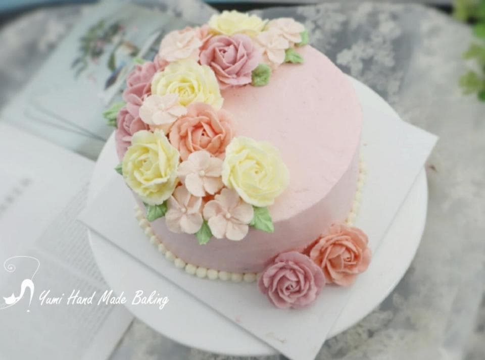 這張照片是一塊粉色蛋糕,上面裝飾著精緻的奶油花,看起來很漂亮。