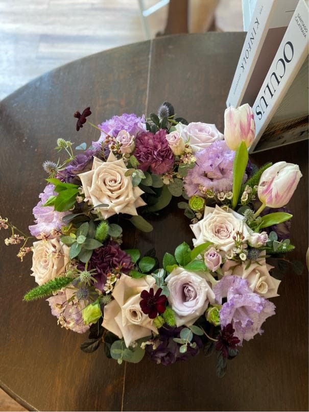 1) 照片顯示一個用紫色、粉紅色和白色玫瑰、紫色康乃馨和草藥組成的花圈
