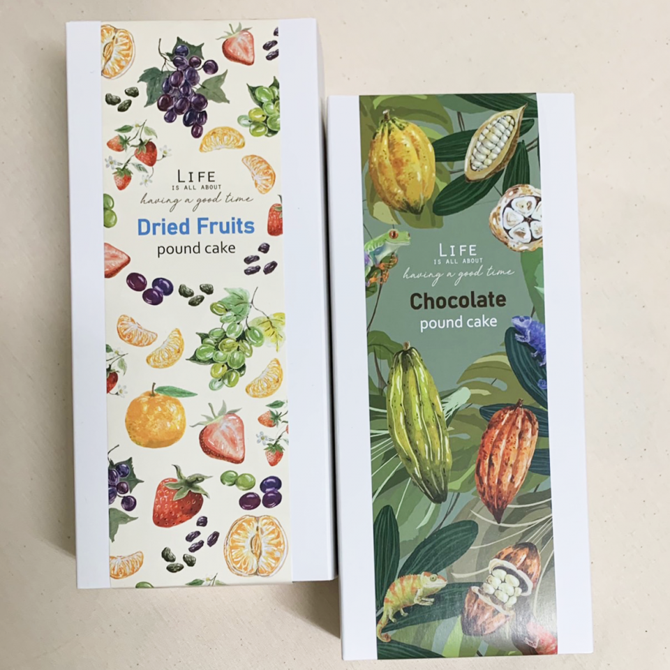 這張照片是兩盒包裝精美的蛋糕禮盒,左側是乾果磅蛋糕,右側是巧克力磅蛋糕。