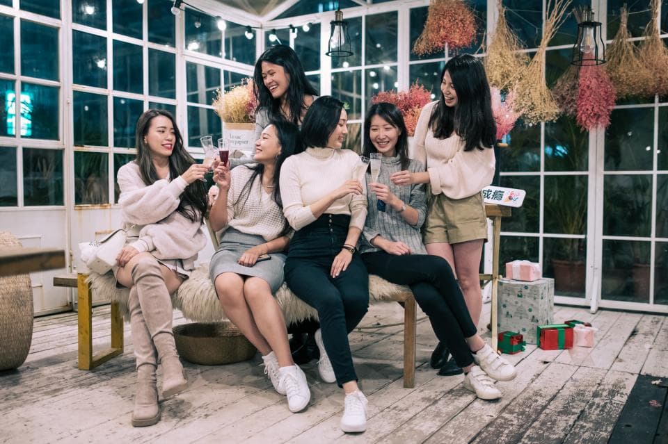 這張照片是五位女性朋友在溫室中聚會,她們各自拿著酒杯,看起來很開心,享受彼此的陪伴。