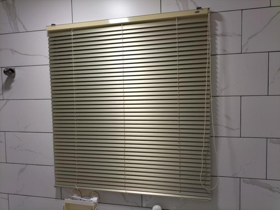 1) 照片顯示一個米色的百葉窗,安裝在浴室牆上