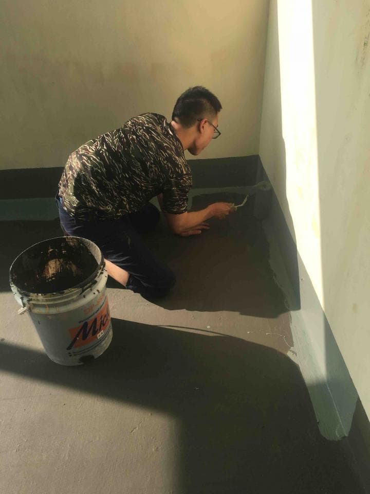 這張照片是一個男人正在用刷子塗抹水泥,他正在進行裝修工程。