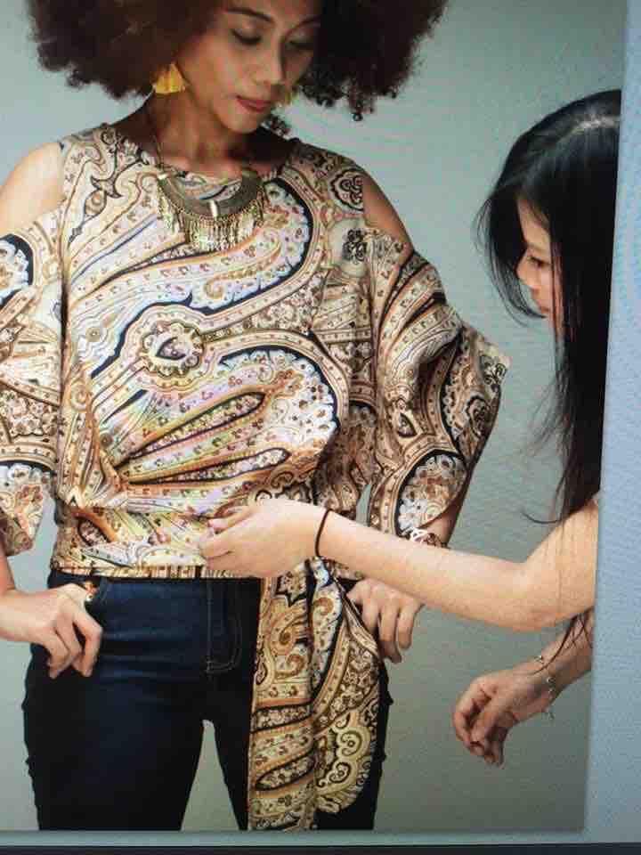 這張照片是一個穿著花色上衣的女孩,另一個女孩正在幫她整理衣服。