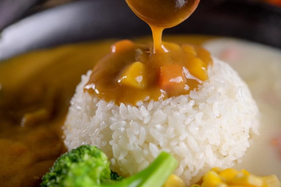 這張「咖哩飯」的照片是一碗白飯淋上黃色的咖哩醬,旁邊有青花菜和玉米。