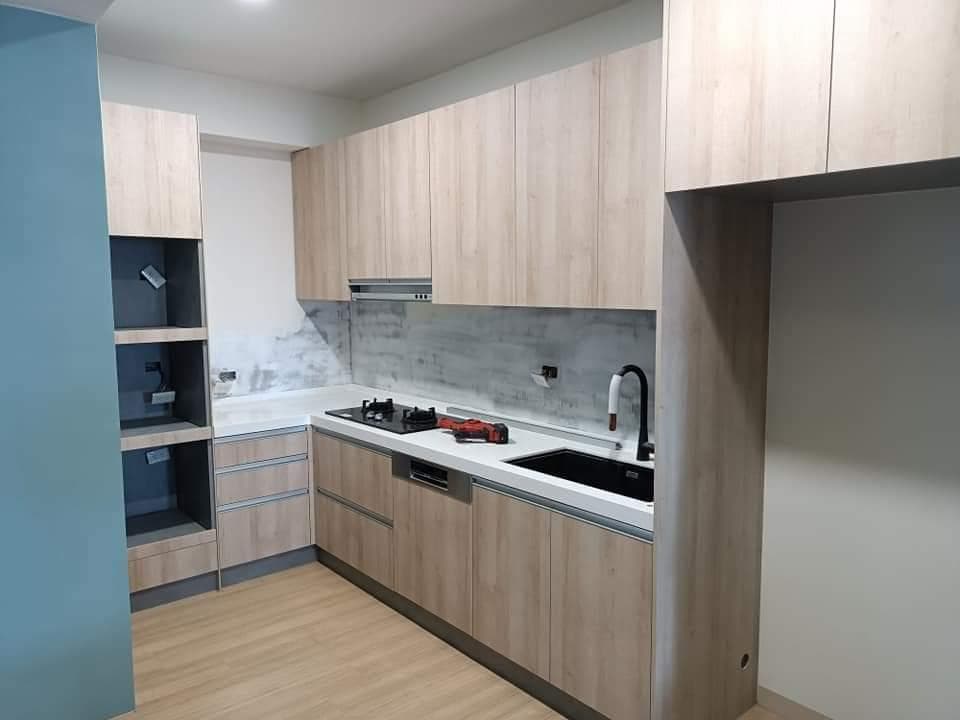 這張照片是一個現代化的廚房,最重要的是L型的流理台,上面有水槽和爐子,旁邊有一個木頭收納櫃,整体空间宽敞明亮,给人一种整洁干净的感觉。