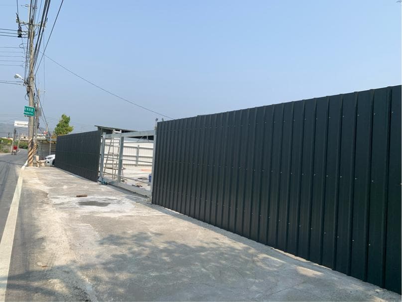 1) 照片顯示一條黑色的金屬圍欄,圍欄前方有一扇白色的金屬門