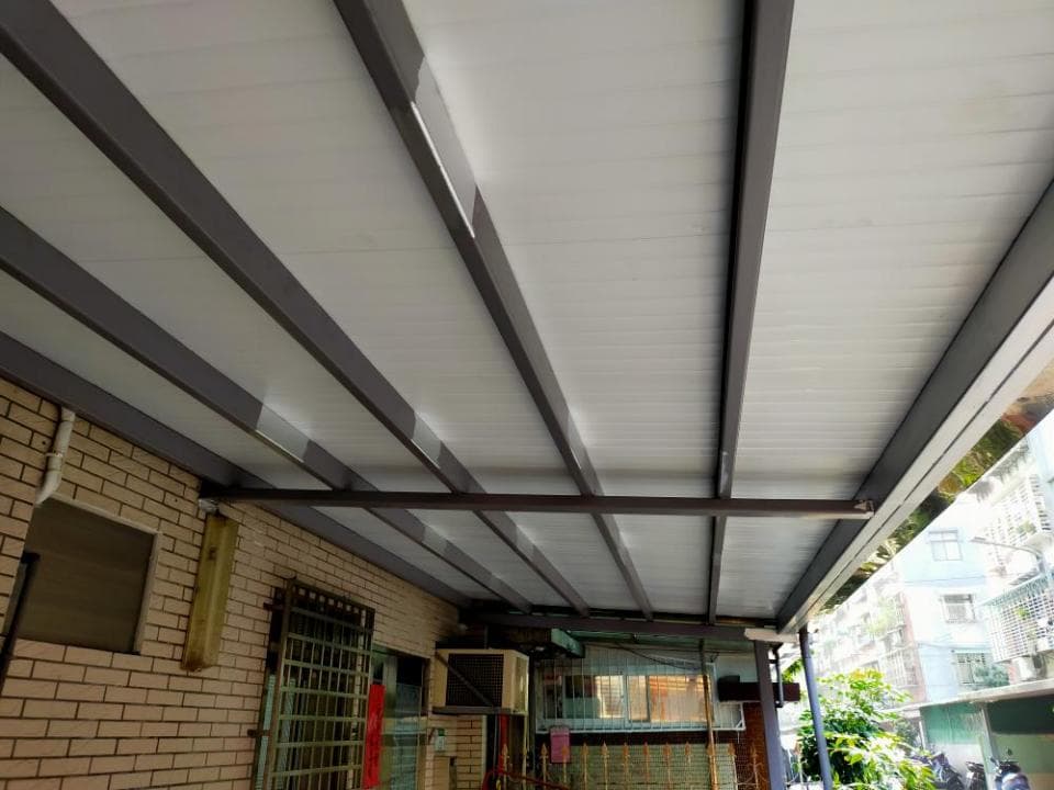 這張「遮陽棚」的照片是一棟房子上的遮陽棚,由多條鋼樑和白色遮陽板組成,可以遮擋陽光和雨水。