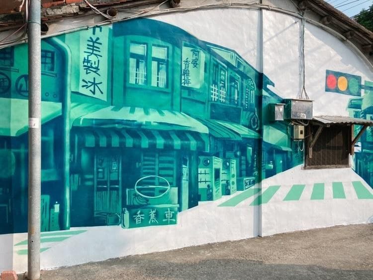 這張「牆壁」的照片是一個街道的塗鴉,畫著綠色的商店和建築,以及斑馬線。