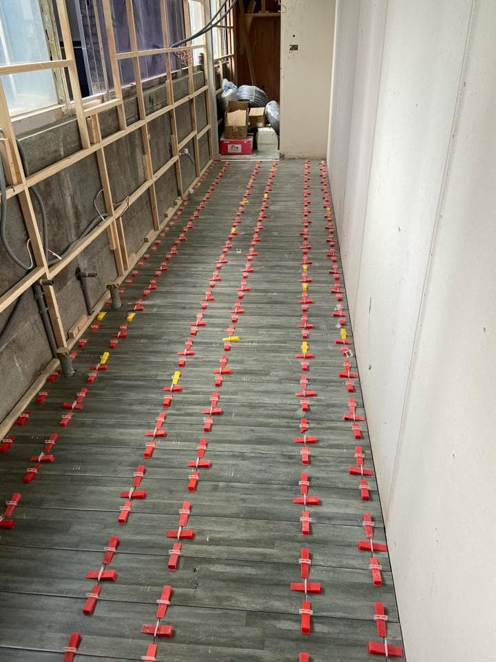 1) 照片顯示一個走廊,地板上鋪設著木地板,木地板間有紅色十字形的間隔