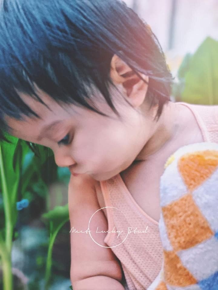 這張照片是一個可愛的小女孩,她穿著粉紅色的背心,手裡拿著一條方格毛巾,她的頭髮是藍色的,臉上露出害羞的笑容。