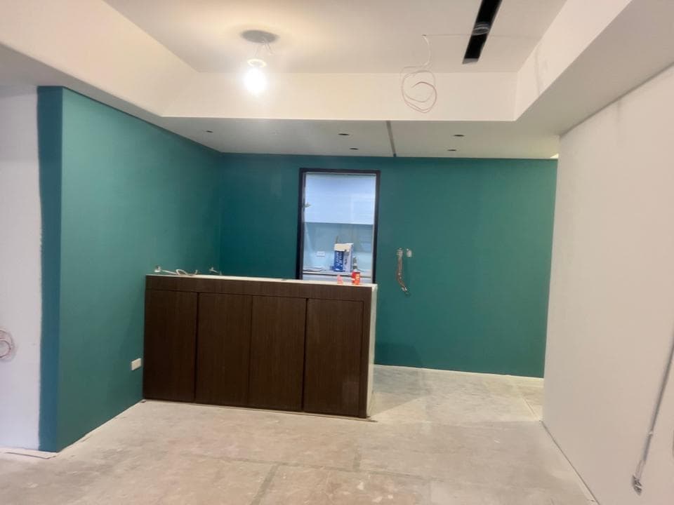 1) 照片顯示一個房間,房間的牆壁是深綠色,地板是白色的,中間有一個木頭的櫃子