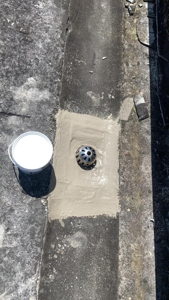 1) 照片顯示一個水泥排水溝,排水溝上有個金屬排水孔,旁邊有一個白色水桶