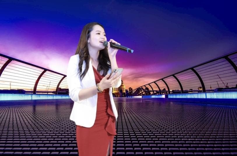 這張照片是一個女人在一個舞臺上唱歌。她穿著白色的外套和紅色的裙子,手拿麥克風唱歌,看起來很投入。