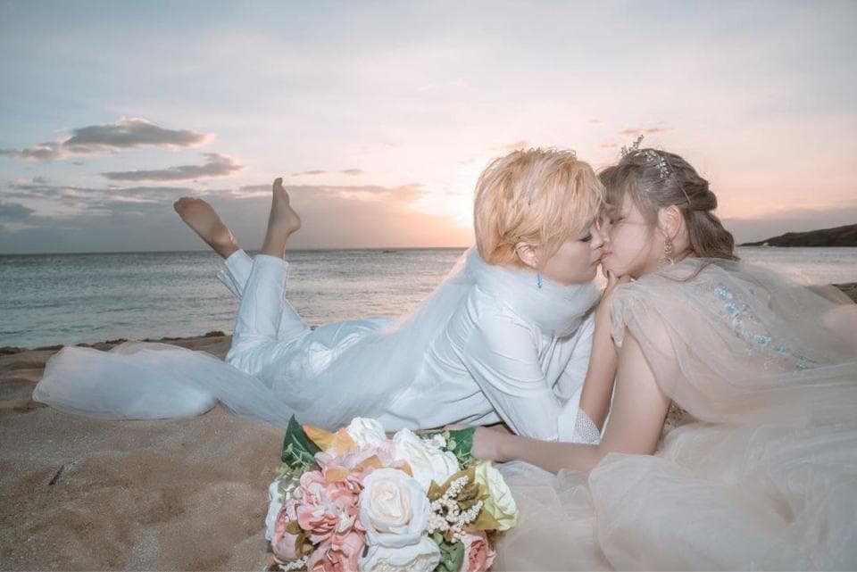 這張照片是一對新人正在沙灘上親吻,他們身穿婚紗,背景是夕陽餘暉。