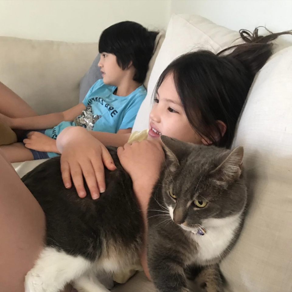 兩個女孩和一隻貓躺在沙發上