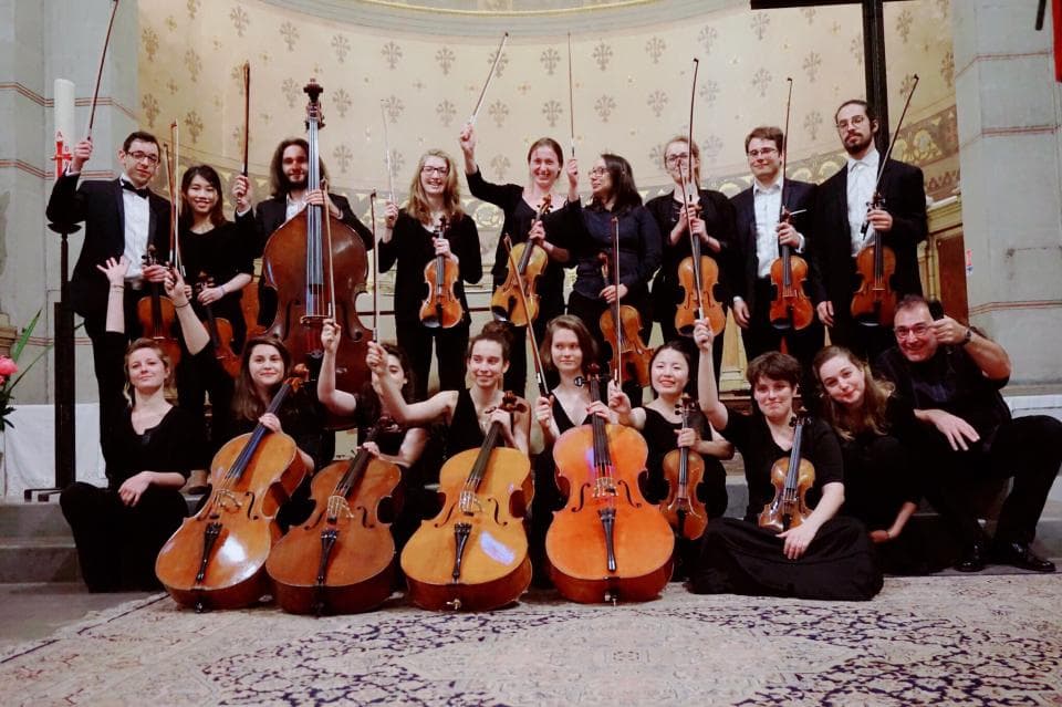 1) 照片中呈現一場弦樂演奏,約 16 位樂手在教堂裡演奏