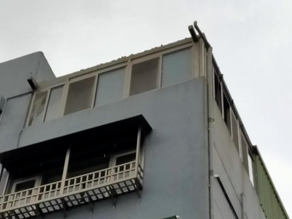 1) 照片顯示一棟建築物的外部,建築物是灰色的,有一排窗户,在窗户下面是一个阳台,阳台上有栏杆