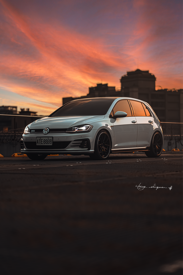 這張「白色汽車」的照片是在夕陽下拍攝的,汽車停在馬路上,背景是建築物和天空。