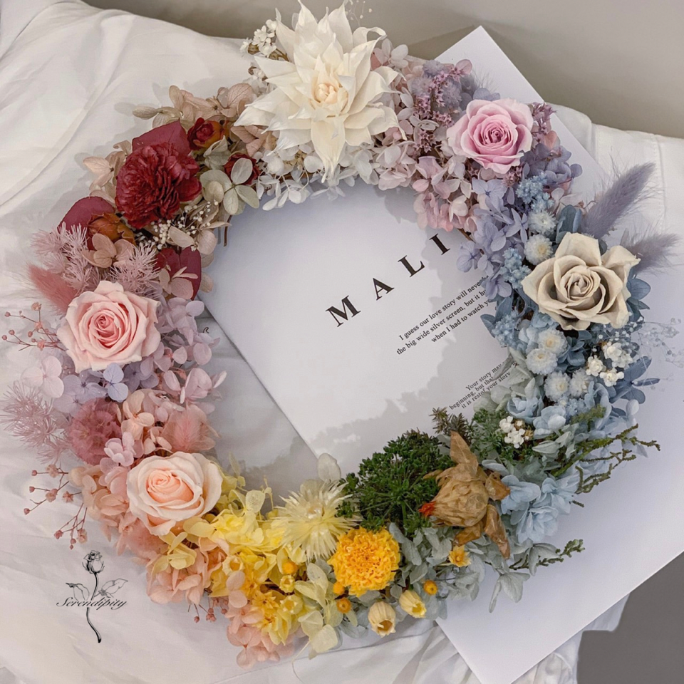 1) 照片顯示一個花環,花環以白色和奶油色花朵為主,包含玫瑰、雛菊和其他花卉