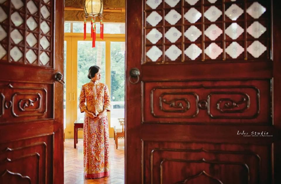 這張照片是一個穿著傳統中式禮服的女子,她站在一扇雕刻精美的木門前,門上的雕花和圖案非常複雜,襯托出女子優雅的氣質。