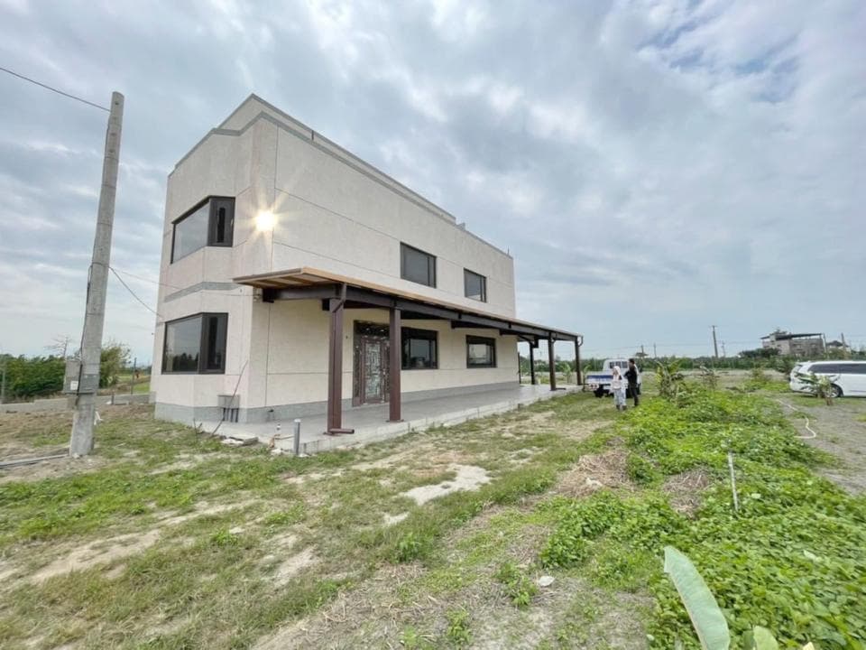 1) 照片顯示一棟白色外牆的現代住宅,房子前方有庭院,以及兩個人站在庭院中