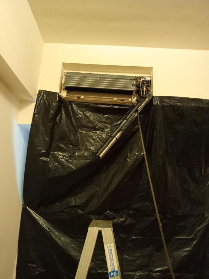 1) 照片中顯示一個被黑色塑膠布覆蓋的房間,房間裡有一台冷氣機,以及一把梯子