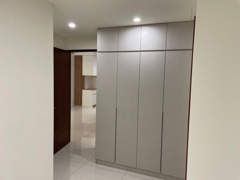 這張照片是一間現代化的公寓,照片中最重要的一部分是牆上的大型衣櫃,它是由六扇白色木門組成,看起來很簡潔、乾淨,而且空間感十足。