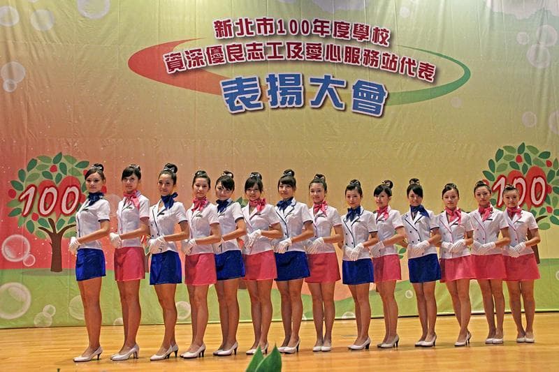 這張「一群女孩穿著制服站在舞臺上」的照片是慶祝「新北市100週年」的活動。