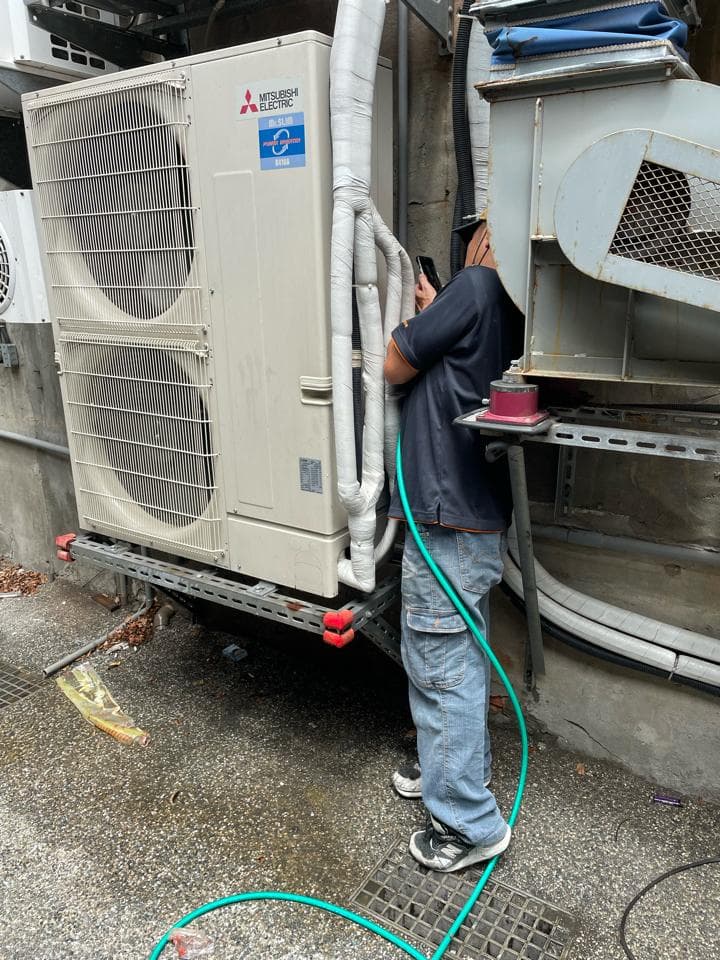 1) 照片顯示一名男子正在檢查室外冷氣機