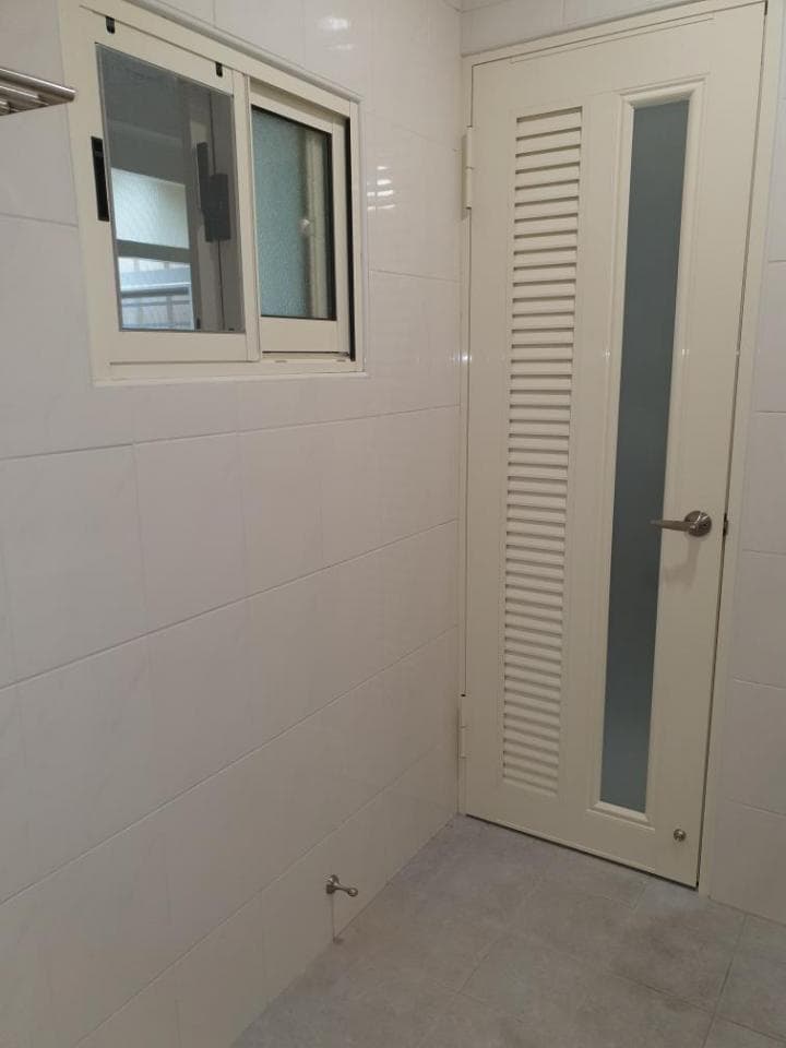 1) 照片顯示一個浴室,其中一面牆上有一扇窗戶,另一面牆上有一扇帶有百葉窗的門