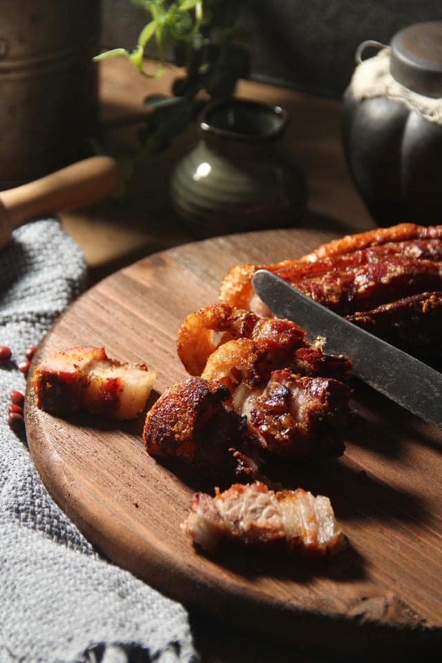 這張「烤肉」的照片是幾片烤好的豬肉放在木板上,旁邊放著一把刀和一些紅豆。