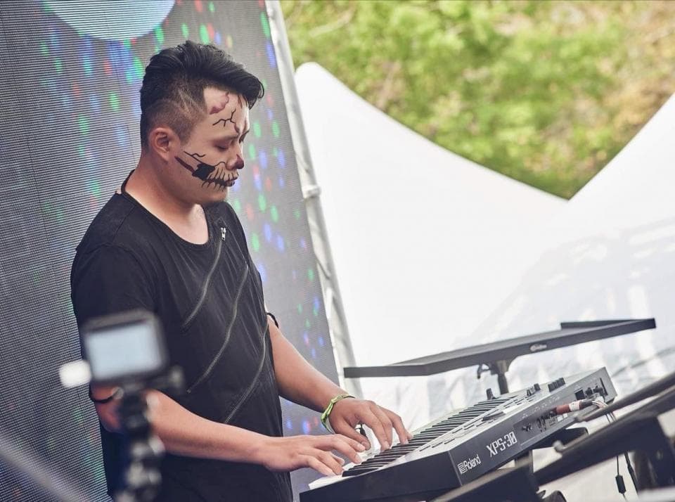 這張照片是一位戴著骷髏面具的男子正在彈奏電子琴。