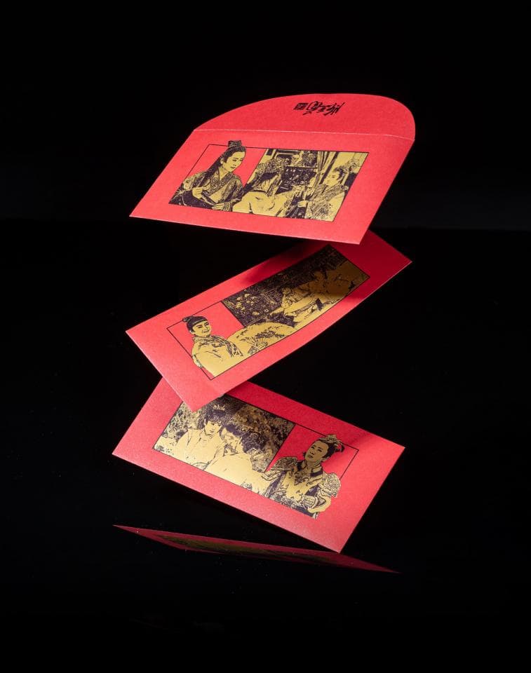 這張照片是三張紅色利是封,上面印有金色的人物圖案。利是封是中國新年時用來裝錢的傳統紅包,象徵著祝福和好運。