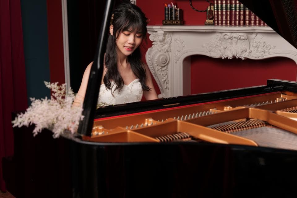 這張「婚紗照」的照片是一名女子坐在鋼琴前,她穿著白色的婚紗,並帶著幸福的笑容。