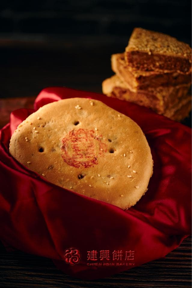 這張照片是一塊圓形的芝麻餅,上面印有紅色圖案,看起來十分可口。