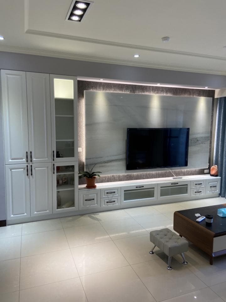 1) 照片顯示一個帶有白色櫥櫃和電視牆的客廳