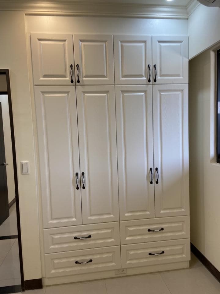 這張照片是一組白色現代化的櫥櫃,有六扇門和三個抽屜,它們被簡潔的黑色把手裝飾着。